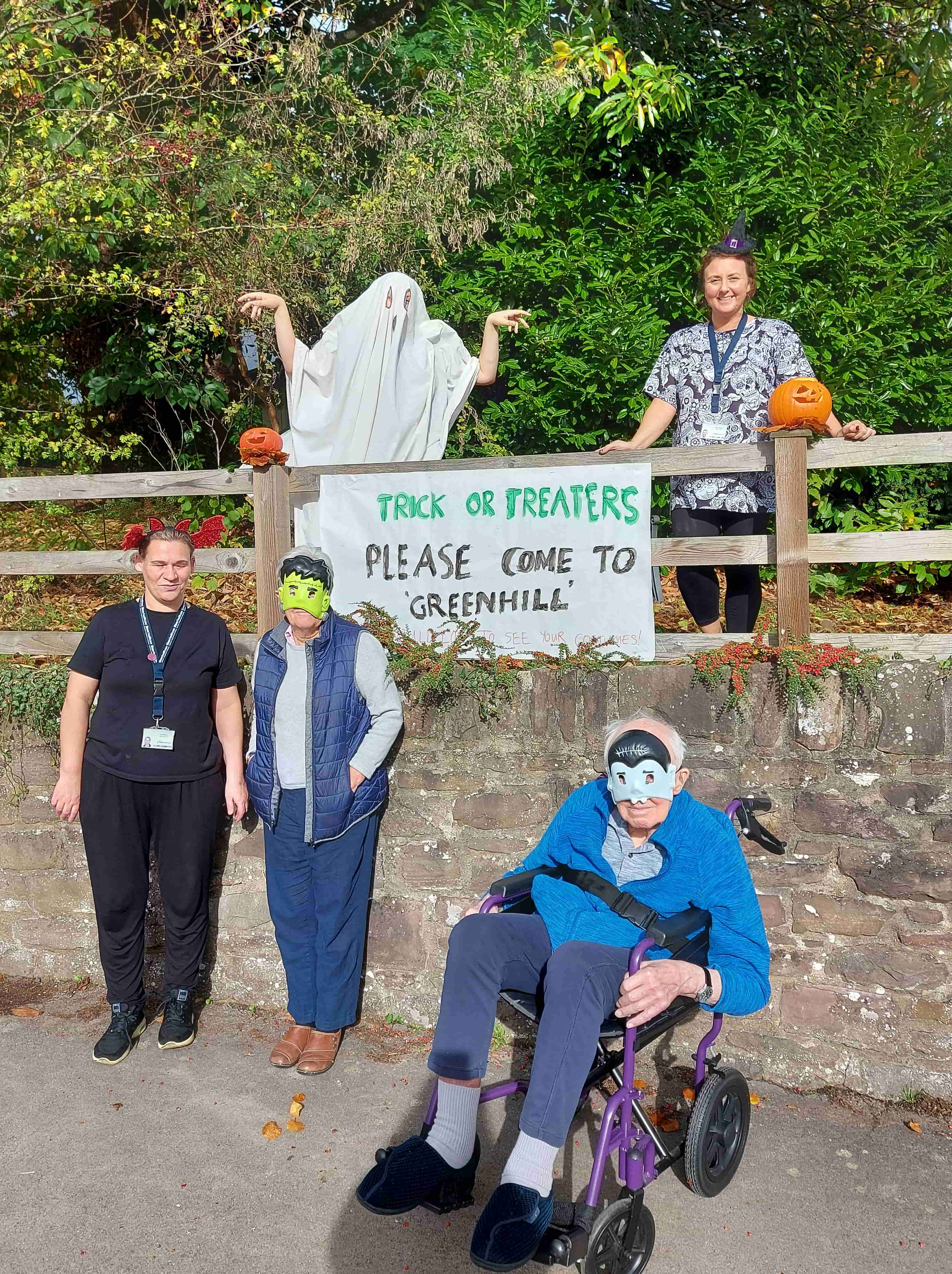 Residents and employees dressed up for Halloween next to the sign that they made