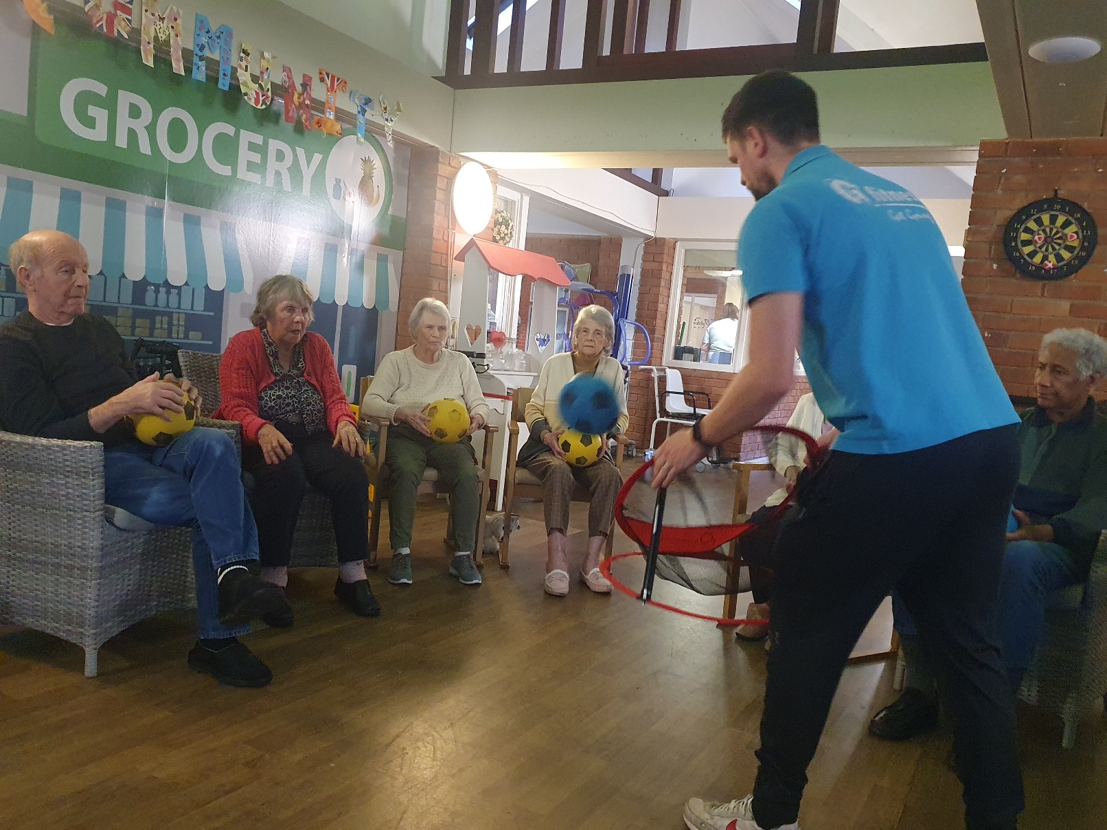 Tom from G Fitness catching a ball that residents are throwing 