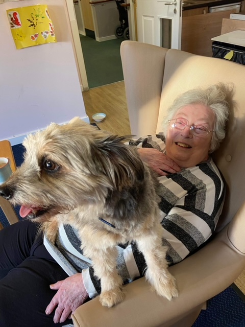 resident sitting with Teddy the dog